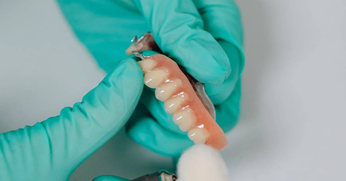 Dentista polindo prótese dentária com ferramenta rotatória